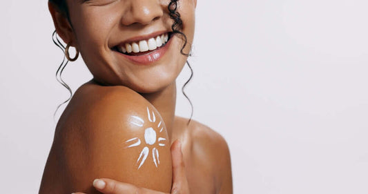 Close-up of a smiling woman with a sun-shaped SPF design on her shoulder, highlighting the importance of sun protection for healthy skin.