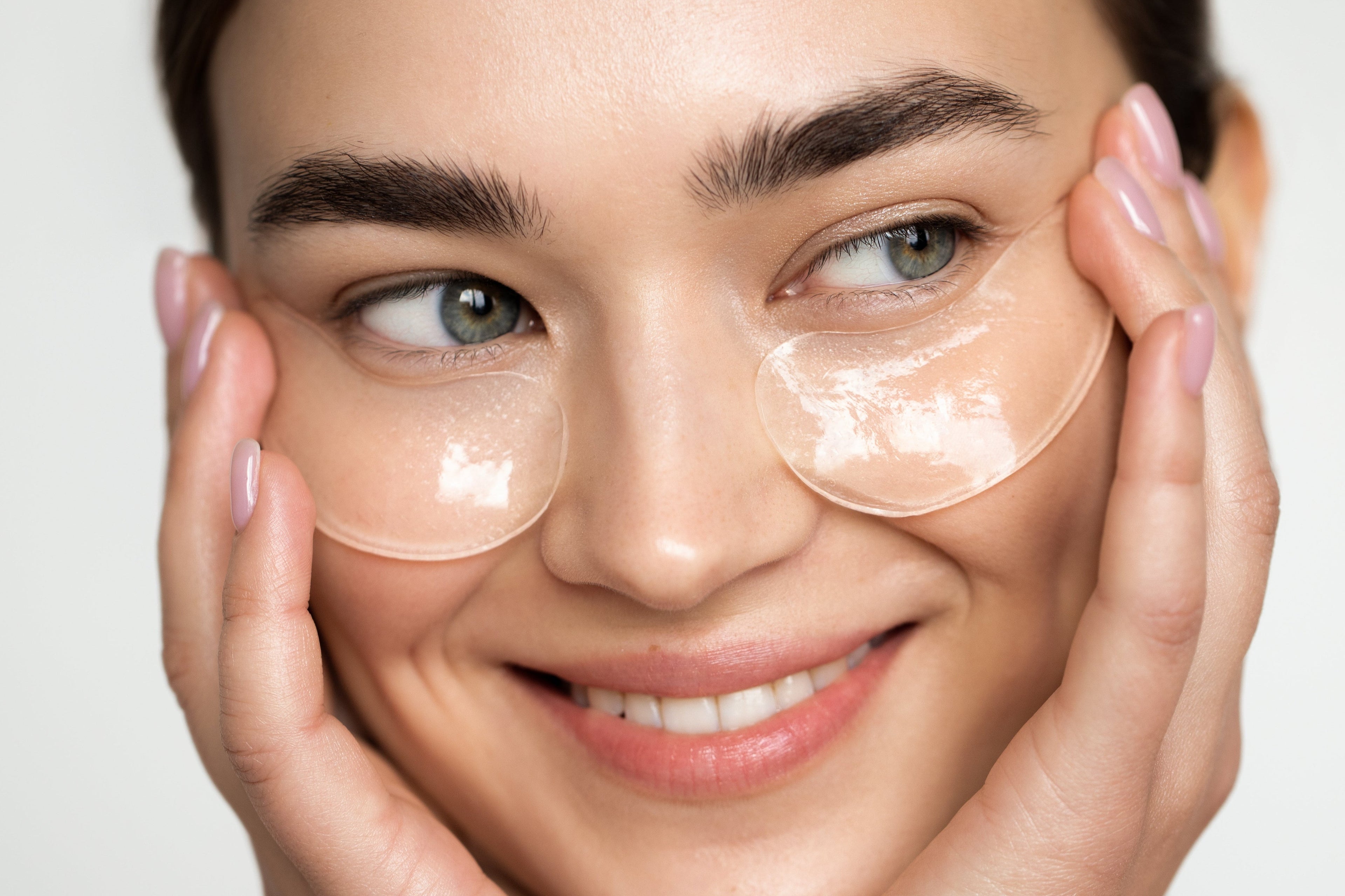 Woman wearing clear eye patches with a plain background